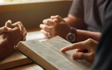 young man reading bible with friends who are praying to God Join the cell group at the church.